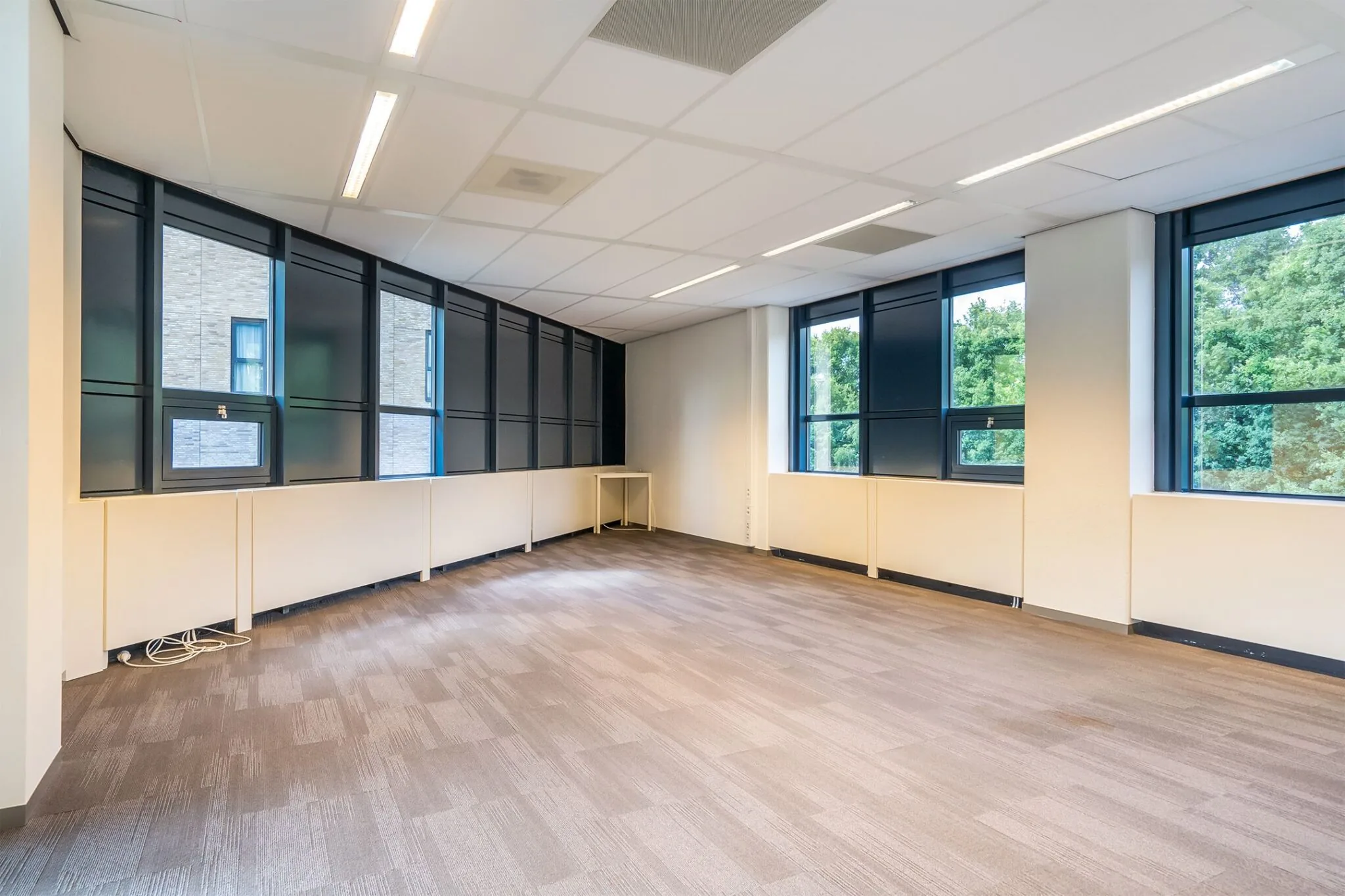 Leeg kantoor met grote ramen en beige tapijtvloer in het gebouw Kanaalpark 140.