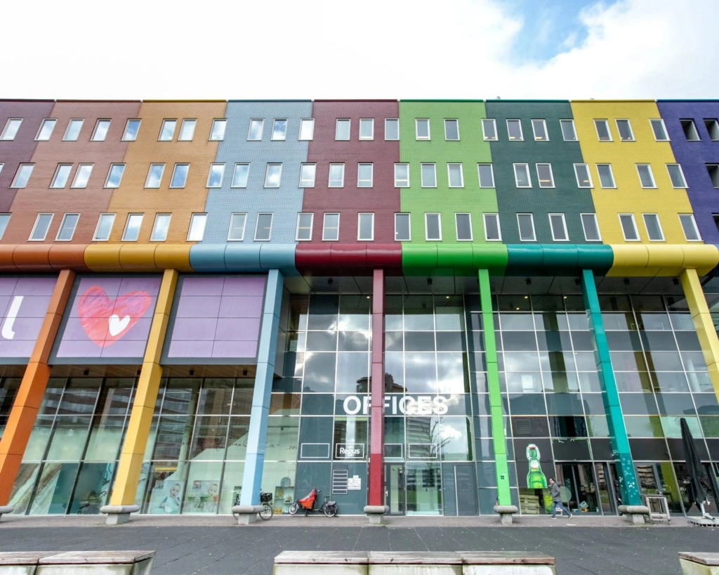 Een kleurrijk kantoorgebouw op de Johan Cruijff Boulevard met grote ramen en een hartvormig kunstwerk.