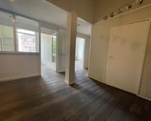 Binnenruimte van een kantoor aan de Weteringschans 130 in Amsterdam met houten vloer, witte wanden en glazen scheidingswanden.