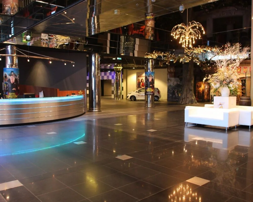 Moderne en ruime kantoorlobby aan de Van Cleeffkade 15 met glanzende vloertegels, een ronde receptiebalie en sfeervolle verlichting.