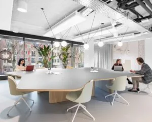 Moderne vergaderruimte in kantoorpand De Walvis aan de Grote Bickersstraat in Amsterdam, met grote tafel, designstoelen en uitzicht op de stad.