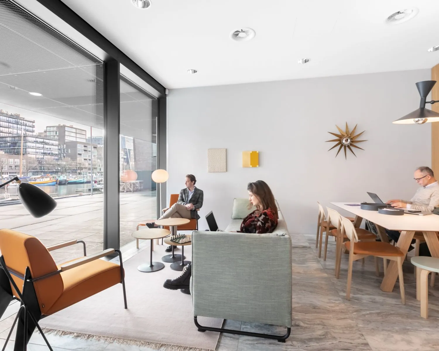 Moderne kantoorruimte in De Walvis aan de Grote Bickersstraat in Amsterdam met uitzicht op het water en mensen aan het werk.