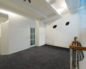 Moderne, lichte kantoorruimte met donker tapijt en glazen deur aan de Herengracht 449a in Amsterdam.