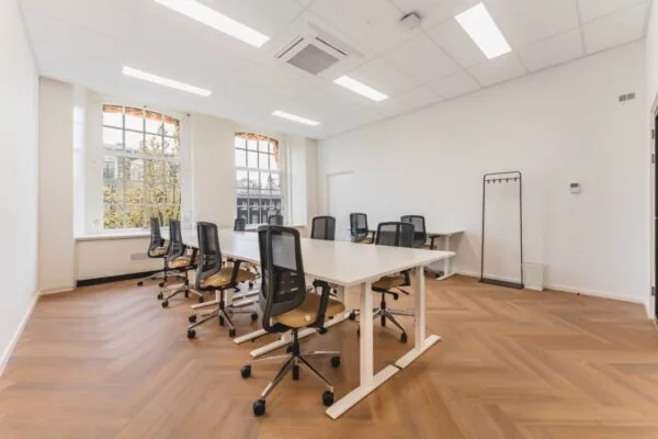 Een lichte en ruime kantoorruimte aan de Herengracht in Amsterdam met meerdere bureaus en stoelen.