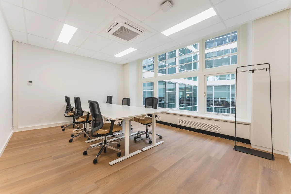 Een moderne vergaderruimte met een lange tafel en bureaustoelen, gelegen aan de Herengracht in Amsterdam.