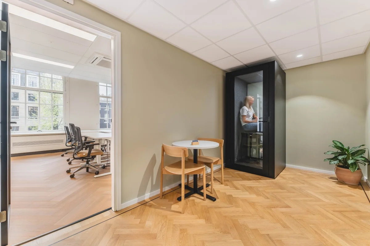Moderne kantoorruimte op de Herengracht in Amsterdam met een vergaderruimte, een tafel met stoelen en een meeting pod.