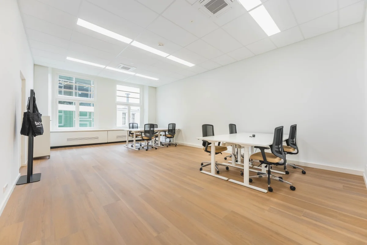 Een ruime, moderne kantoorruimte met houten vloeren en bureaus op Herengracht 471 in Amsterdam.