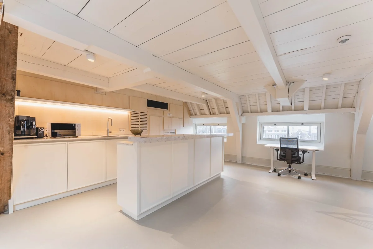 Een moderne kantoorruimte met keuken en bureau in een lichte, open zolderruimte op de Keizersgracht in Amsterdam.