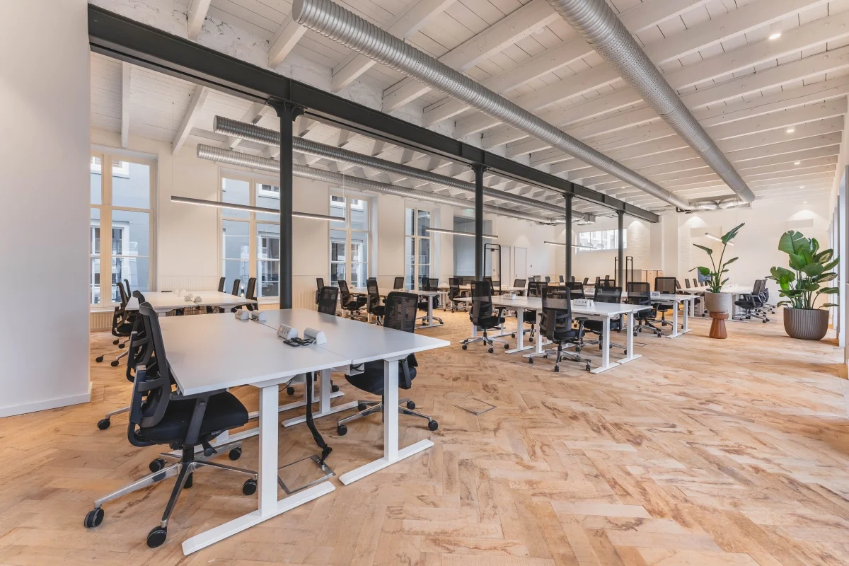 Een moderne, ruime kantoorruimte op de Keizersgracht 125-127 in Amsterdam met meerdere bureaus en stoelen.