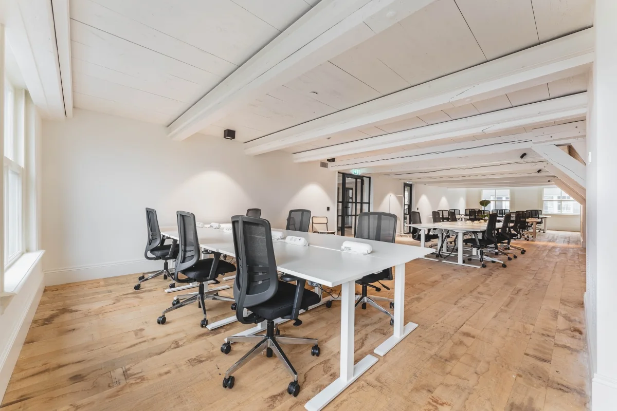 Moderne kantoorruimte op de Keizersgracht 125-127 in Amsterdam met houten vloeren en witte bureaus.