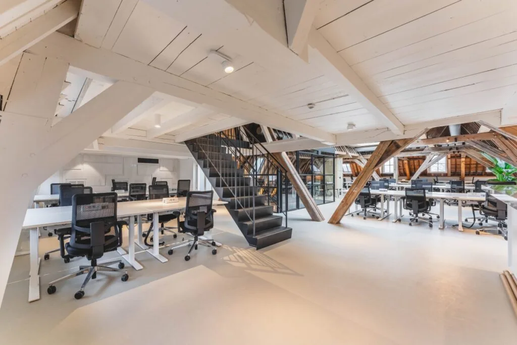 Moderne kantoorruimte met open houten balken en bureaus met bureaustoelen in Amsterdam aan de Keizersgracht.