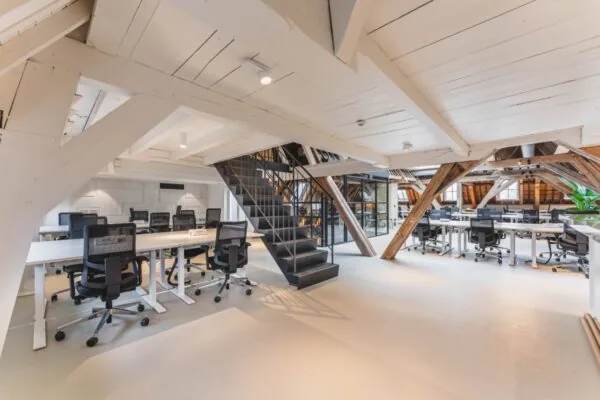 Moderne kantoorruimte met open houten balken en bureaus met bureaustoelen in Amsterdam aan de Keizersgracht.