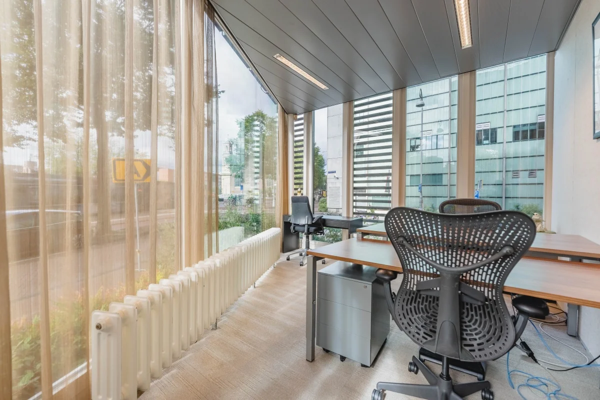 Moderne kantoorruimte met grote ramen en bureaus aan de Muiderstraat in Amsterdam.