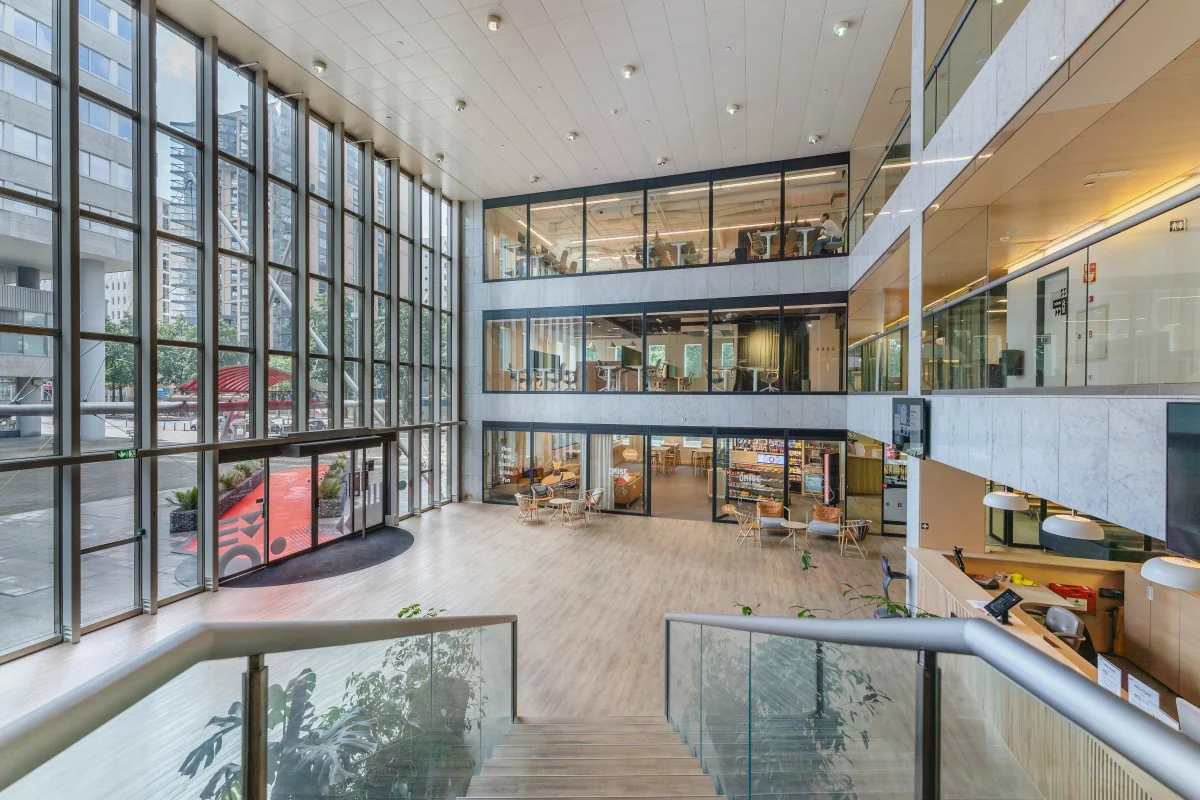 Moderne ontvangstruimte van een kantoor met grote ramen en glazen balustrade bij Koningin Wilhelminaplein.
