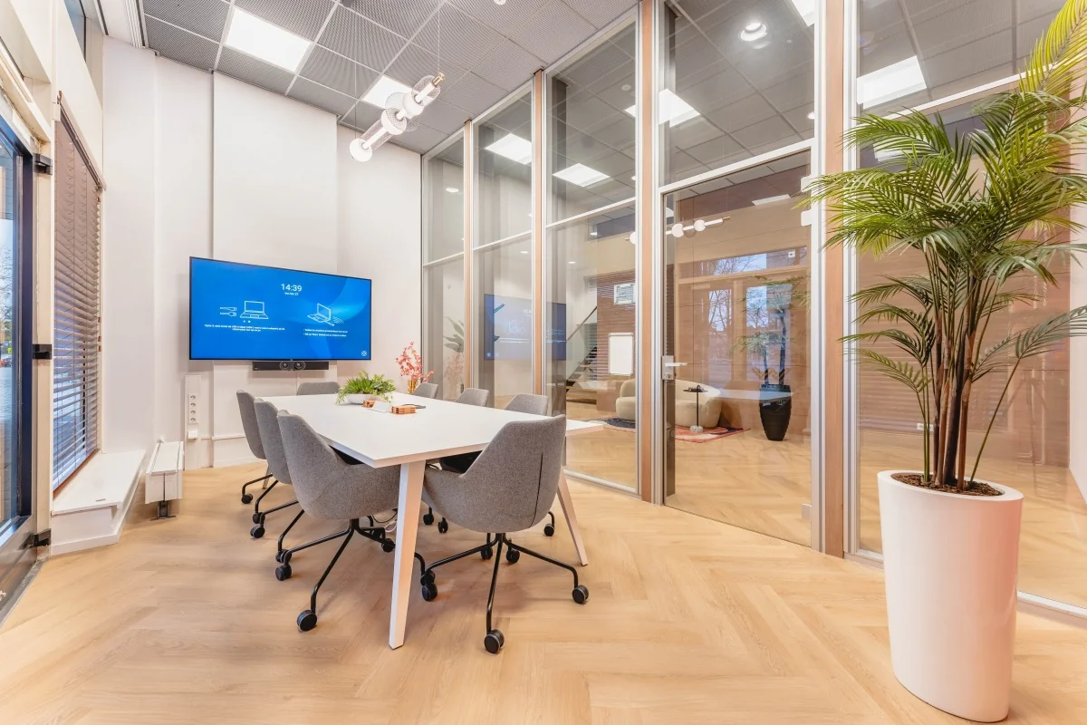 Moderne vergaderruimte op Weesperstraat 107 met glazen wanden, een groot scherm en een strakke inrichting.