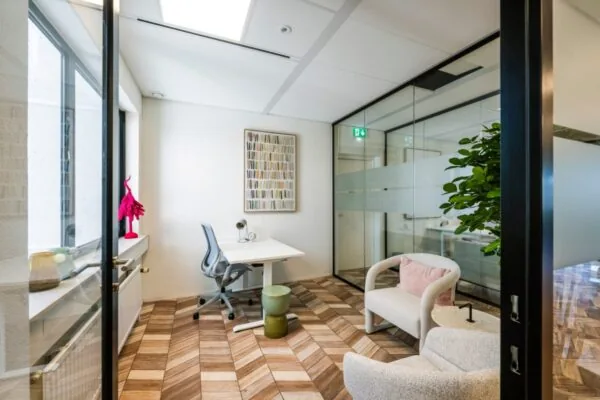 Moderne kantoorruimte met glazen muren, houten vloer, bureau en comfortabele stoelen.