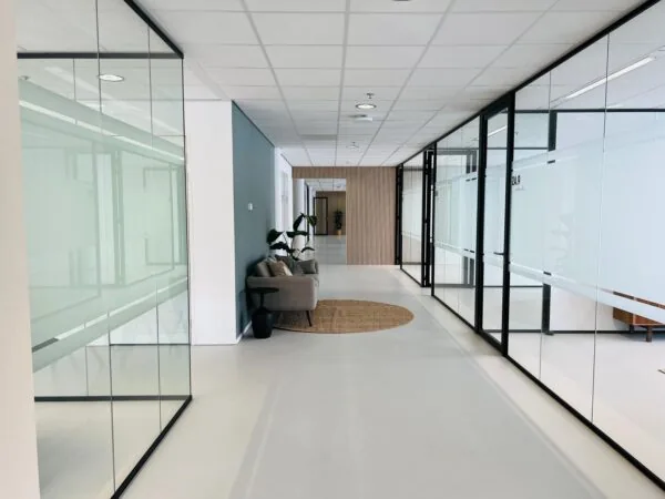 Moderne kantoorruimte aan het Kruisplein 480 in Rotterdam met glazen wanden en een loungehoek.