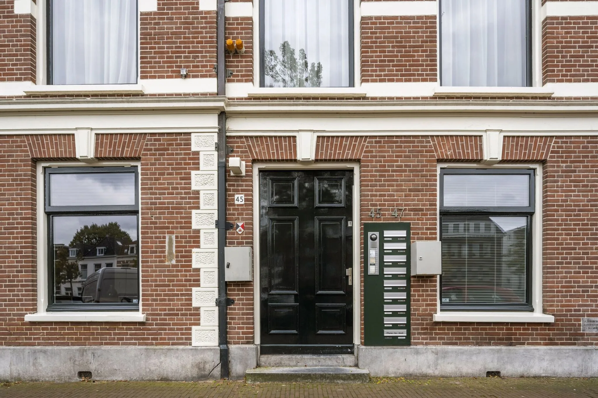 Voorgevel van het kantoorpand aan de Nieuwe Gracht 45-47 in Haarlem met zwarte voordeur en brievenbussen.
