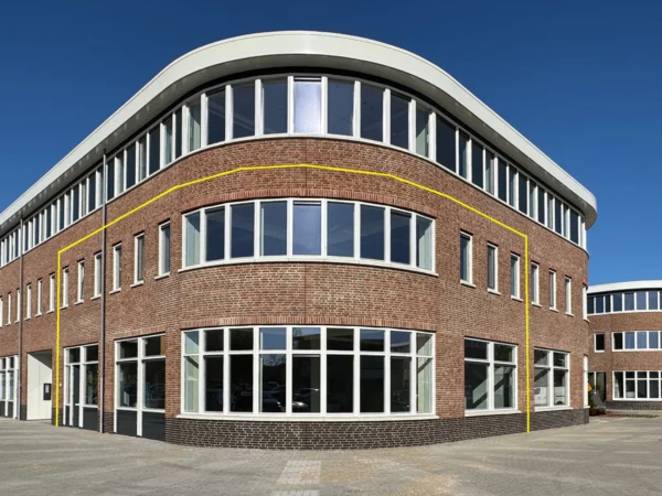 Modern office building for rent at Nijverheidslaan 10 in Weesp, featuring large windows and a curved brick facade.
