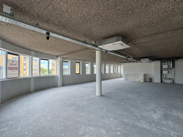 Empty office space for rent at Nijverheidslaan 10 in Weesp with large windows and industrial ceiling.
