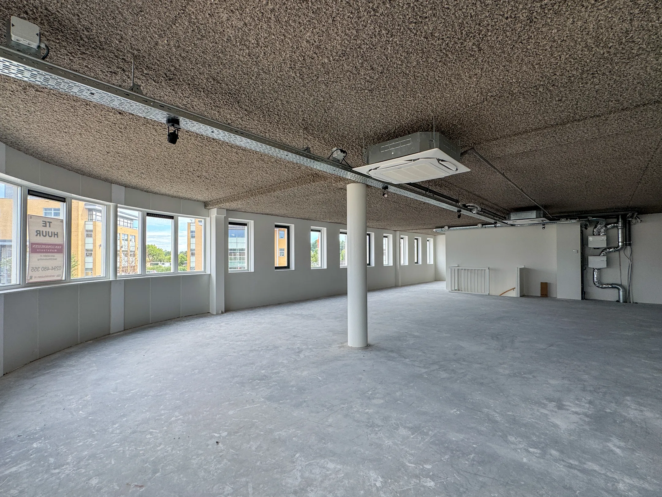 Empty office space for rent at Nijverheidslaan 10 in Weesp with large windows and industrial ceiling.