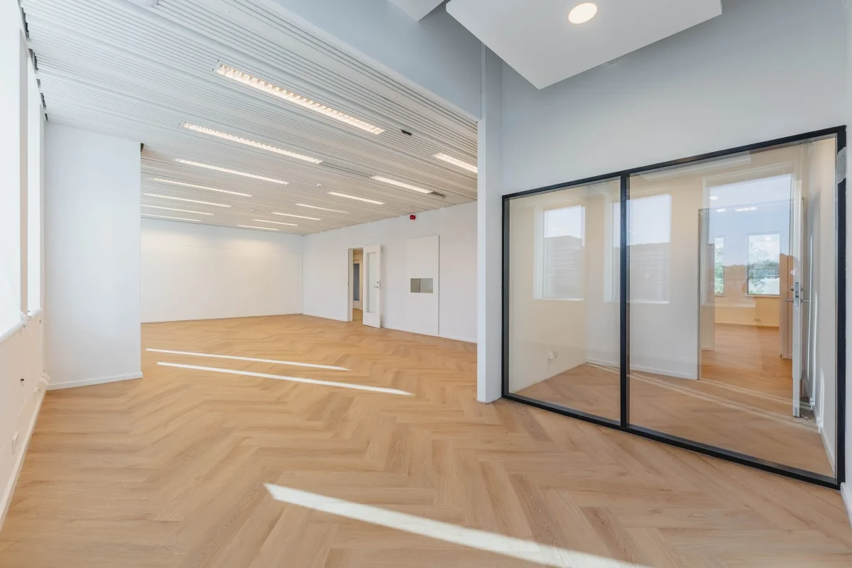 Moderne, lichte kantooruimte aan de Weesperstraat 107 met houten visgraatvloer en glazen scheidingswanden.