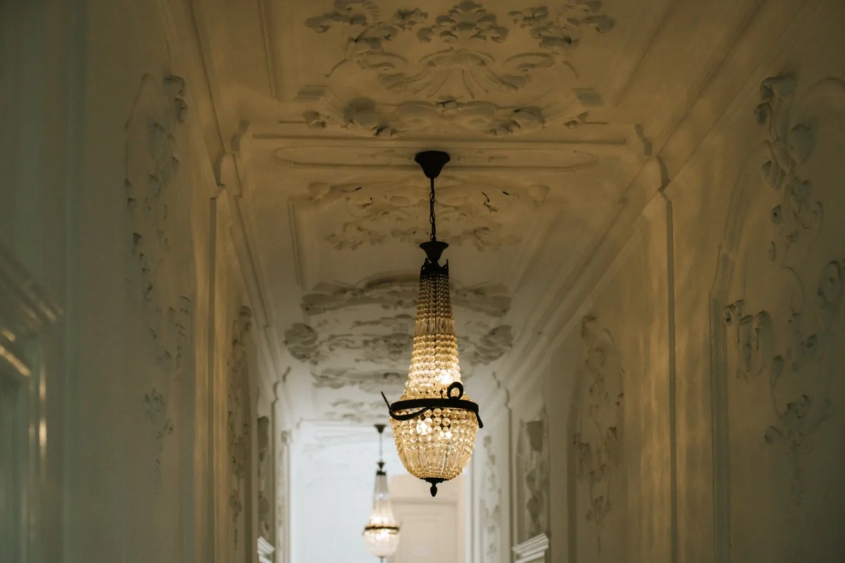 Sierlijke gang met kroonluchters en rijk gedecoreerd stucwerk aan het plafond in Keizersgracht 64.