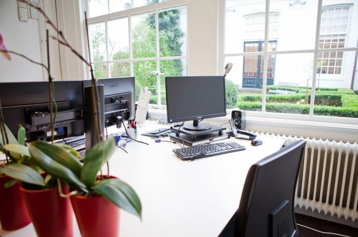 Modern kantoor bij Keizersgracht 97 met werkplekken en uitzicht op een groene binnentuin.