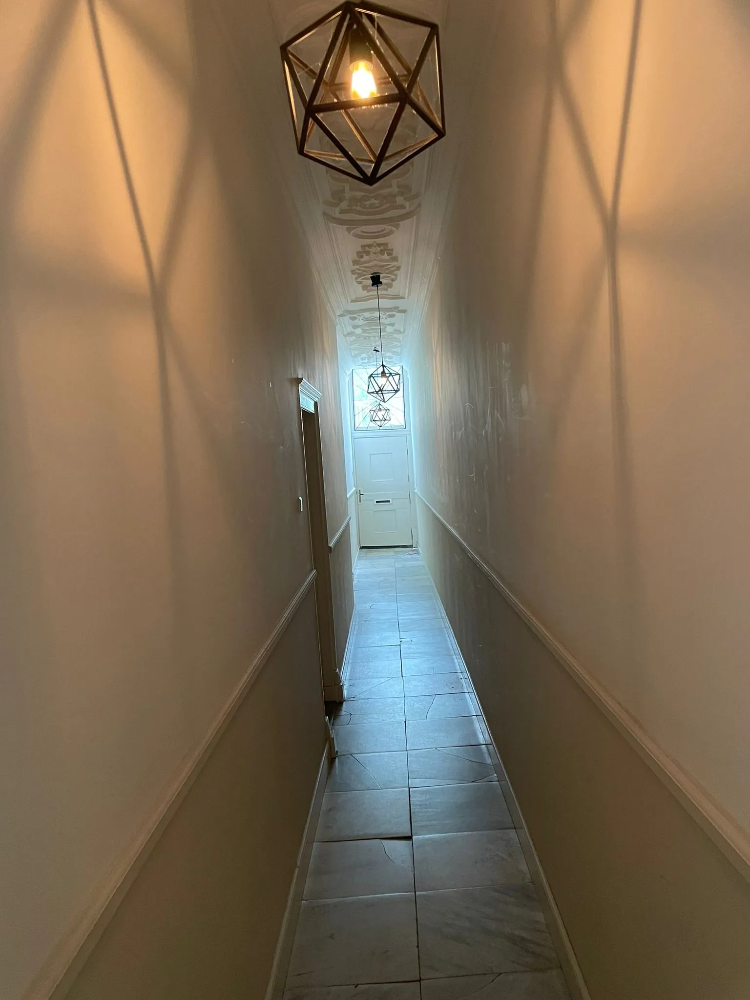 Smal verlicht gangpad met versierde plafondlijsten en geometrische hanglampen in Kloveniersburgwal 56.