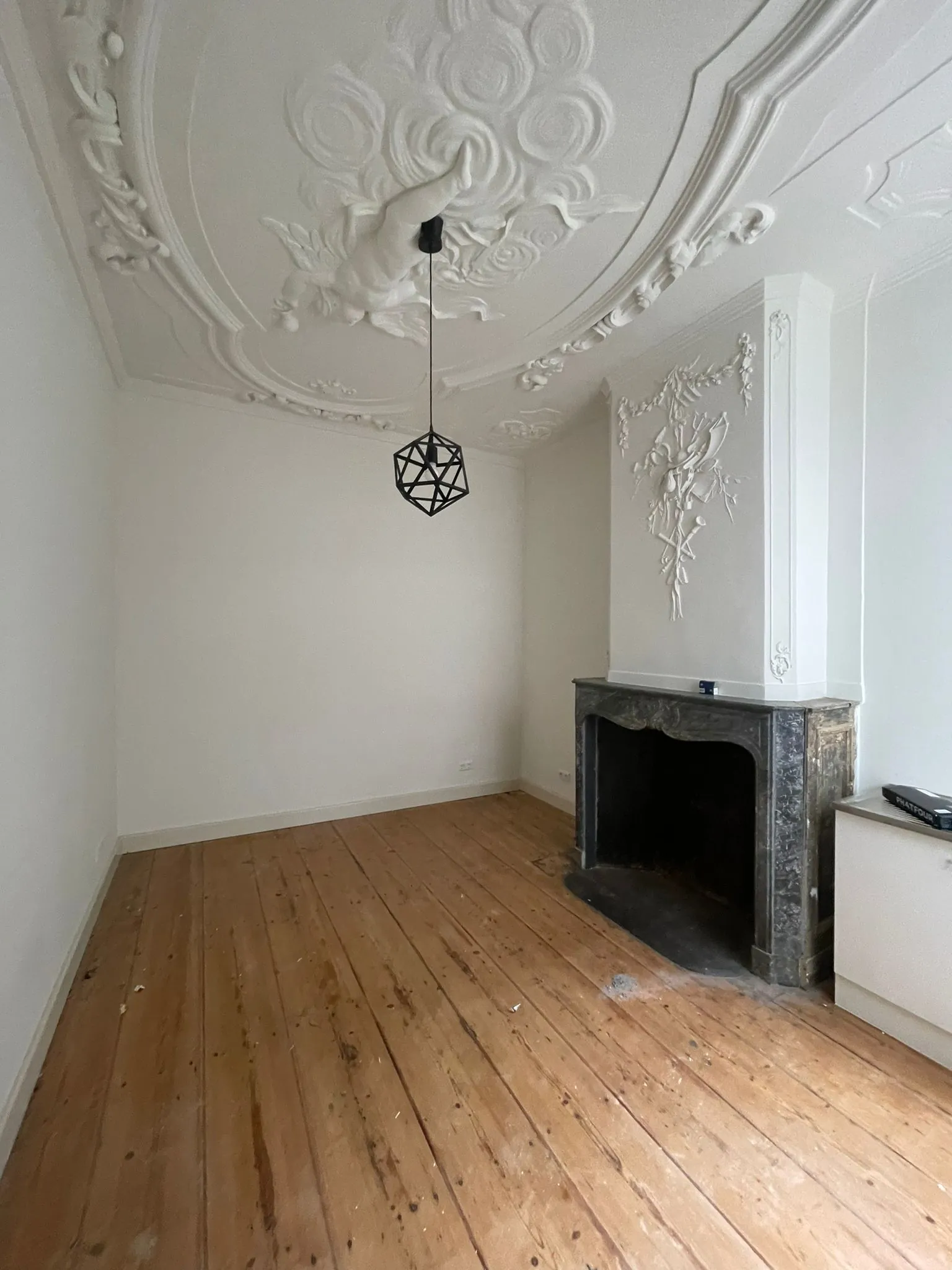 Lege kamer in Kloveniersburgwal 56 met houten vloer, sierplafond en marmeren open haard.