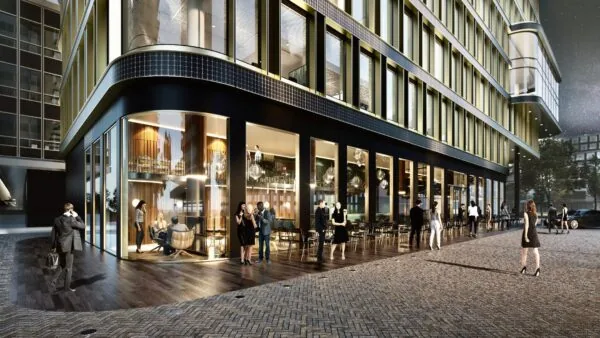 Mensen verzamelen zich buiten een modern, verlicht kantoorgebouw aan het Koningin Wilhelminaplein 4 in de avond.