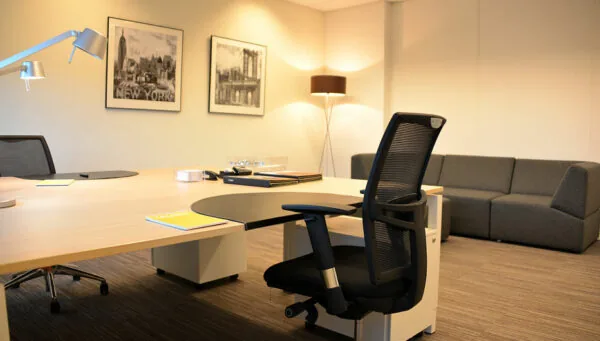 Modern ingericht kantoor aan de Laan van Vredenoord 33 met bureau, bureaustoel, bank en wanddecoratie.