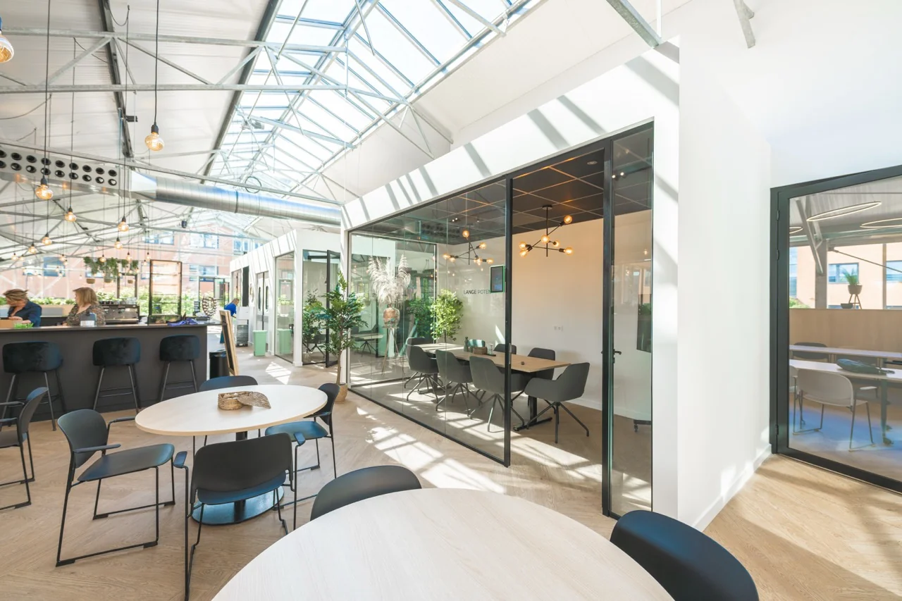 Een moderne en lichte vergaderruimte genaamd Lange Poten 3, omgeven door glazen wanden in een open kantooromgeving.