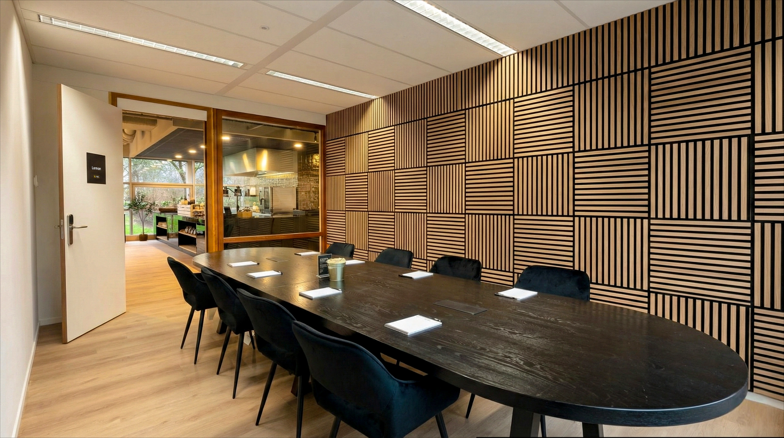Vergaderruimte met een grote ovale tafel, zwarte stoelen en een uniek geometrisch patroon op de muur.