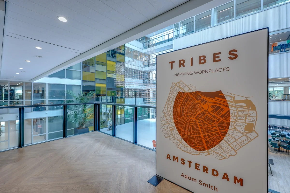 Open, moderne kantoorruimte in Tribes Amsterdam met een bord dat inspiratie en locatie benadrukt.