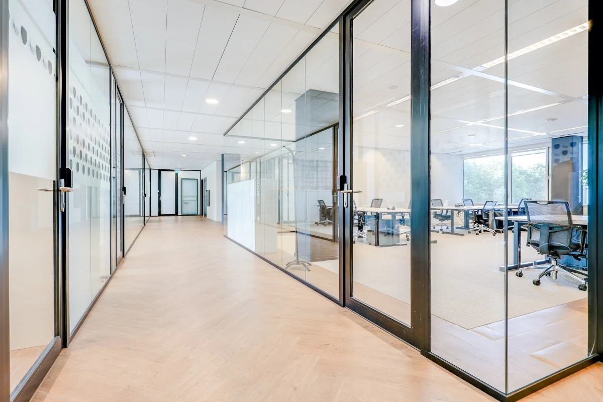 Een moderne kantoorhal in Tribes Amsterdam met glazen wanden en houten vloeren.
