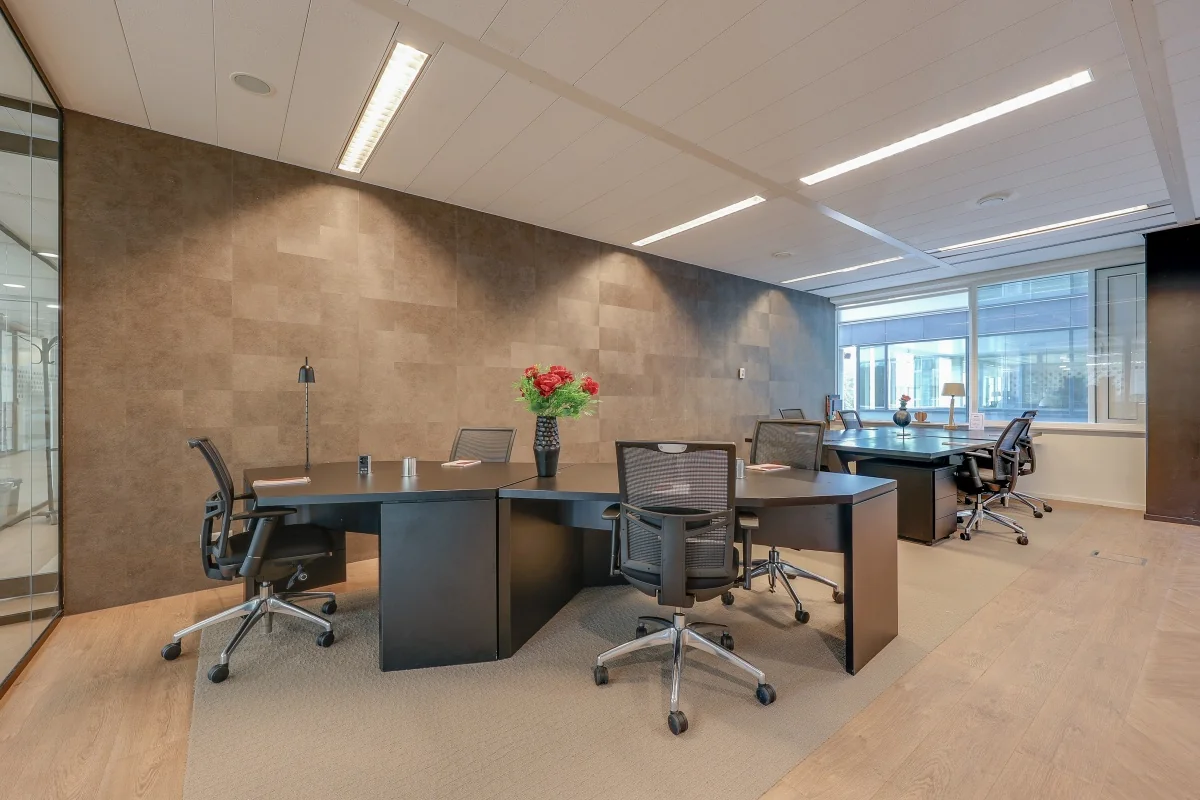 Een moderne coworking ruimte bij Tribes Amsterdam met bureaus, stoelen en bloemen op de tafels.