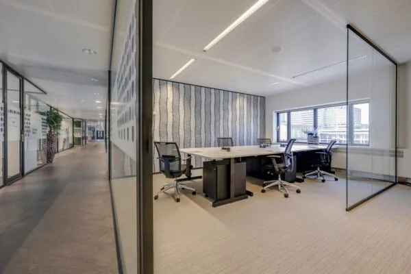 Een moderne privé-kantoorruimte in Tribes Amsterdam Amstel, met een glazen wand en een vergadertafel.