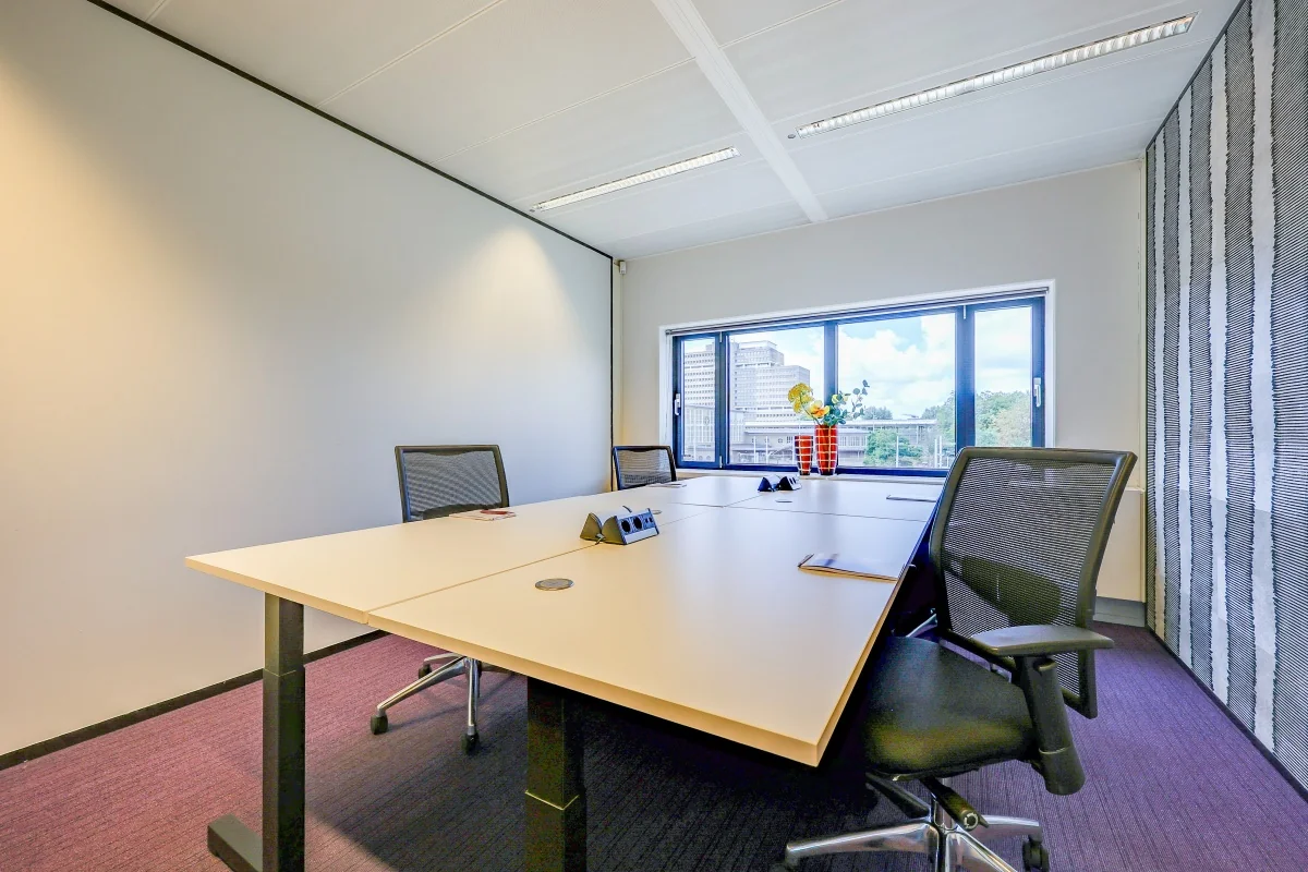 Een moderne kantoorruimte met een grote tafel, stoelen en een raam met uitzicht op de stad.