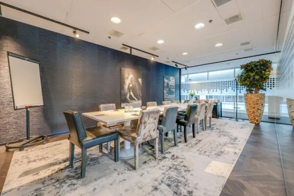 Vergaderruimte bij Tribes Amsterdam South Axis ITO met een lange tafel, stijlvolle stoelen, blauwe wanddecoratie en grote planten.