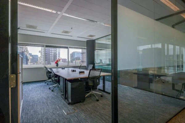 Een moderne privé-kantoorruimte met een grote vergadertafel en stoelen, omgeven door glazen wanden, in Tribes Amsterdam South Axis ITO.