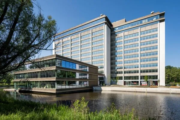 Modern kantoorgebouw aan de Nachtwachtlaan 20 met grote ramen en vijver op de voorgrond.