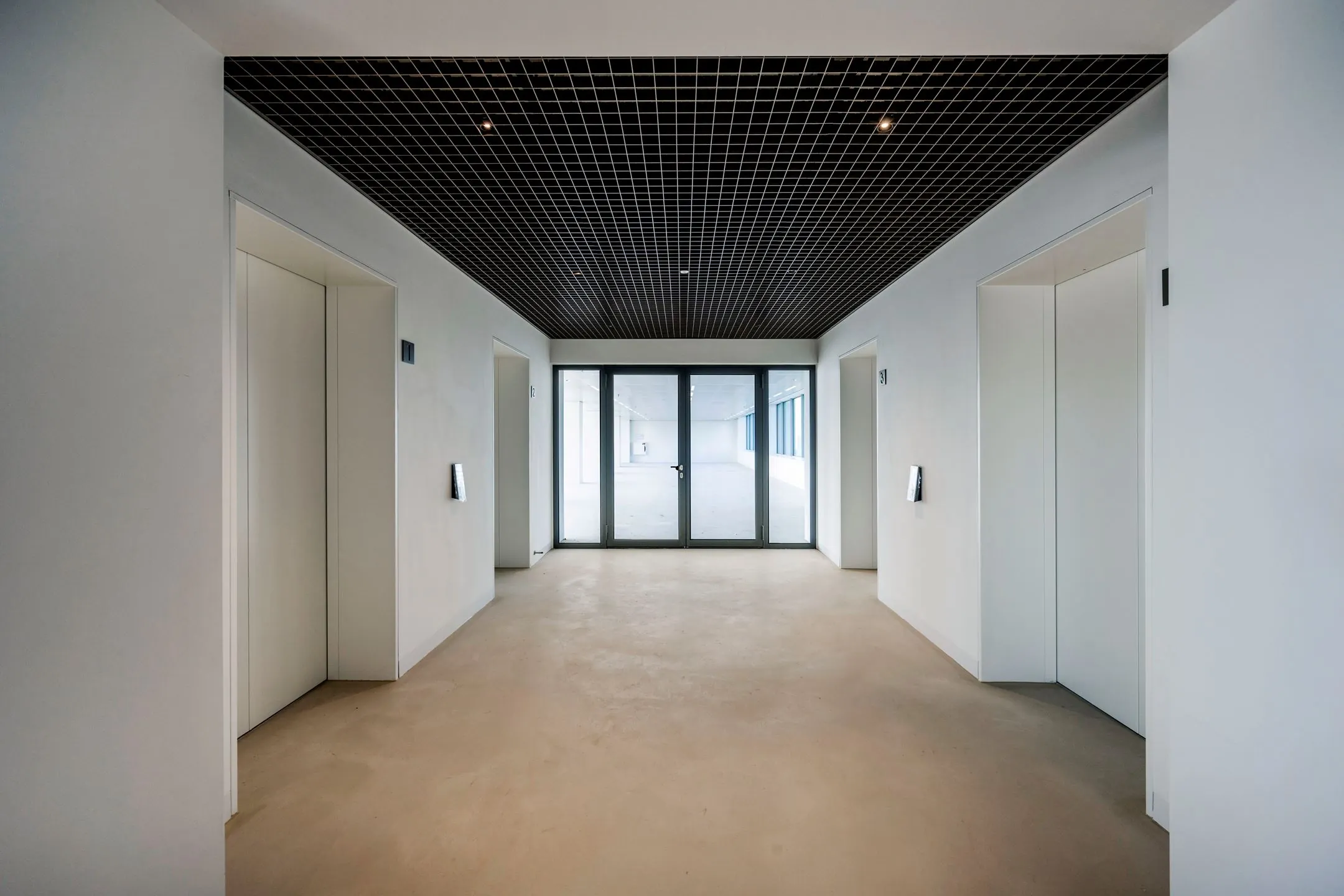 Moderne liftlobby met vier liften en glazen deuren bij Nachtwachtlaan 20.