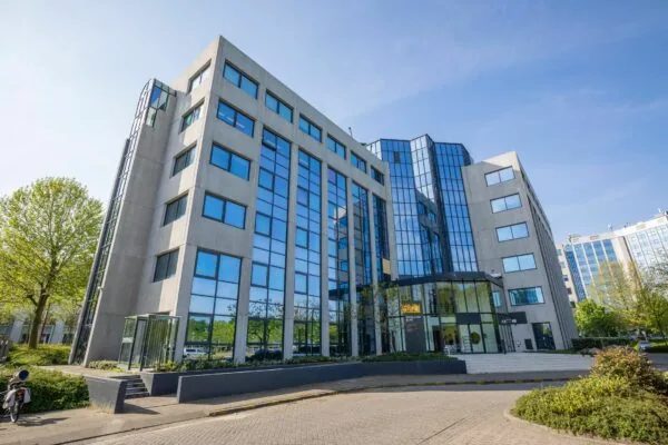 Modern kantoorgebouw aan de Nevelgaarde 8 met spiegelende glasgevel en betonnen elementen.