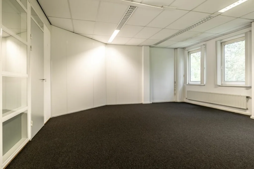 Leeg kantoorruimte met witte wanden, systeemplafond en ramen aan de rechterkant in Paardeweide 2A-4C.