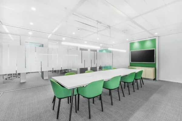 Moderne vergaderruimte aan de Papendorpseweg 95 met een lange witte tafel, groene stoelen en een groot presentatiescherm.