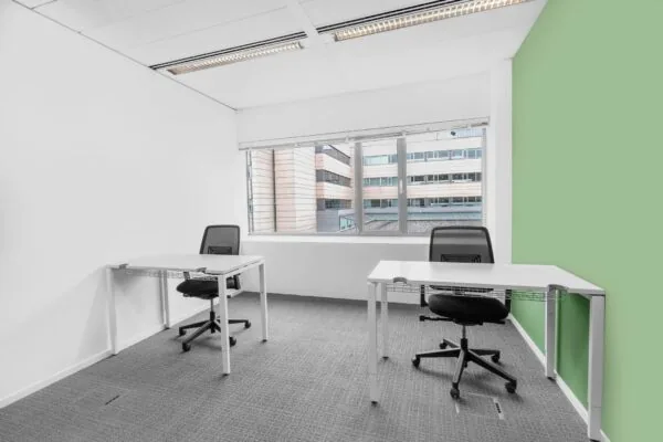 Twee moderne bureaus met bureaustoelen in een lichte kantoorruimte aan de Papendorpseweg 95, met uitzicht op een tegenoverliggend kantoorgebouw.