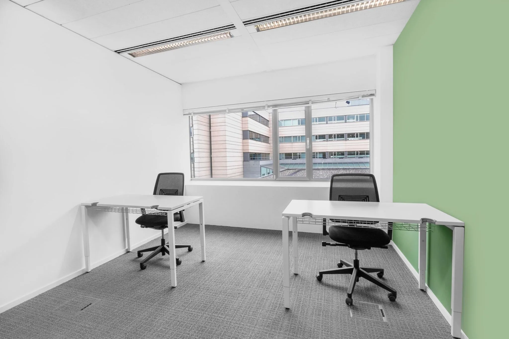 Twee moderne bureaus met bureaustoelen in een lichte kantoorruimte aan de Papendorpseweg 95, met uitzicht op een tegenoverliggend kantoorgebouw.