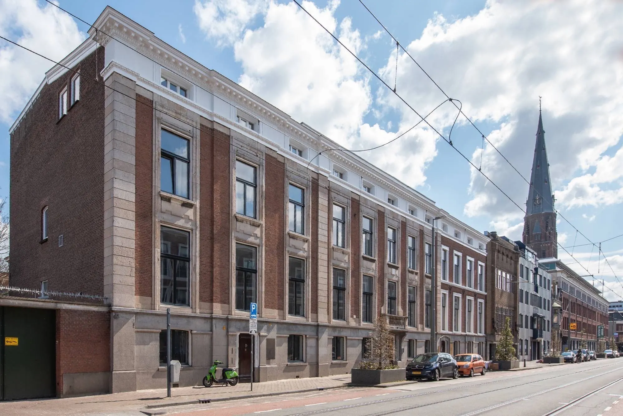 Voorgevel van het pand aan Parkstraat 183 in Den Haag met een rij geparkeerde auto's en een groene deelscooter op de stoep.