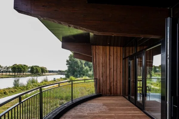 Houten terras met glazen deuren en uitzicht op een rivierlandschap bij Plaatweg 15.